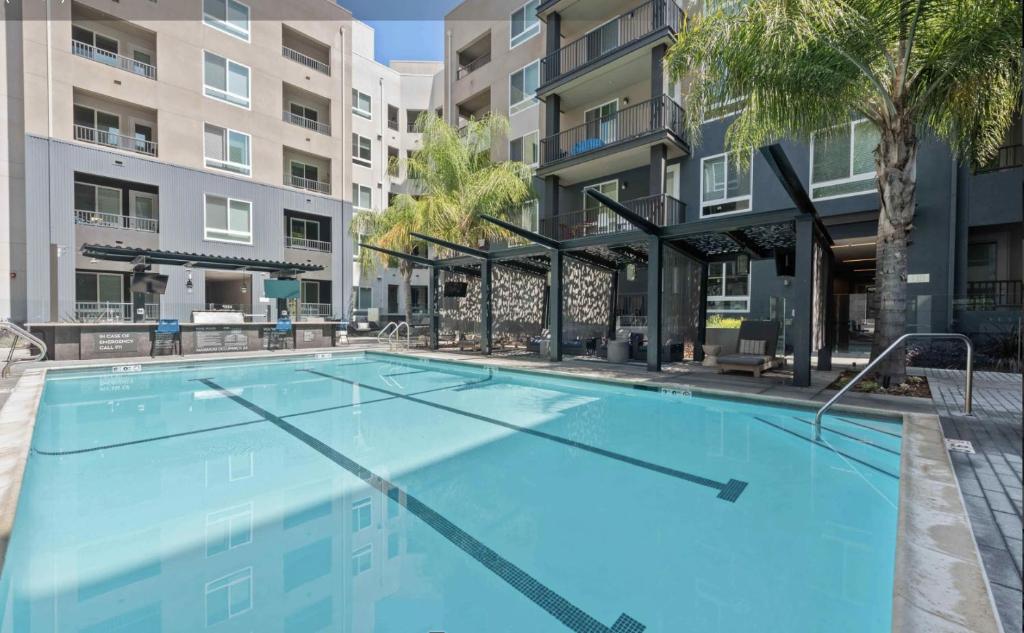 a large swimming pool with palm trees and buildings at Luxury Condo with Pool & Gym ! in Glendale