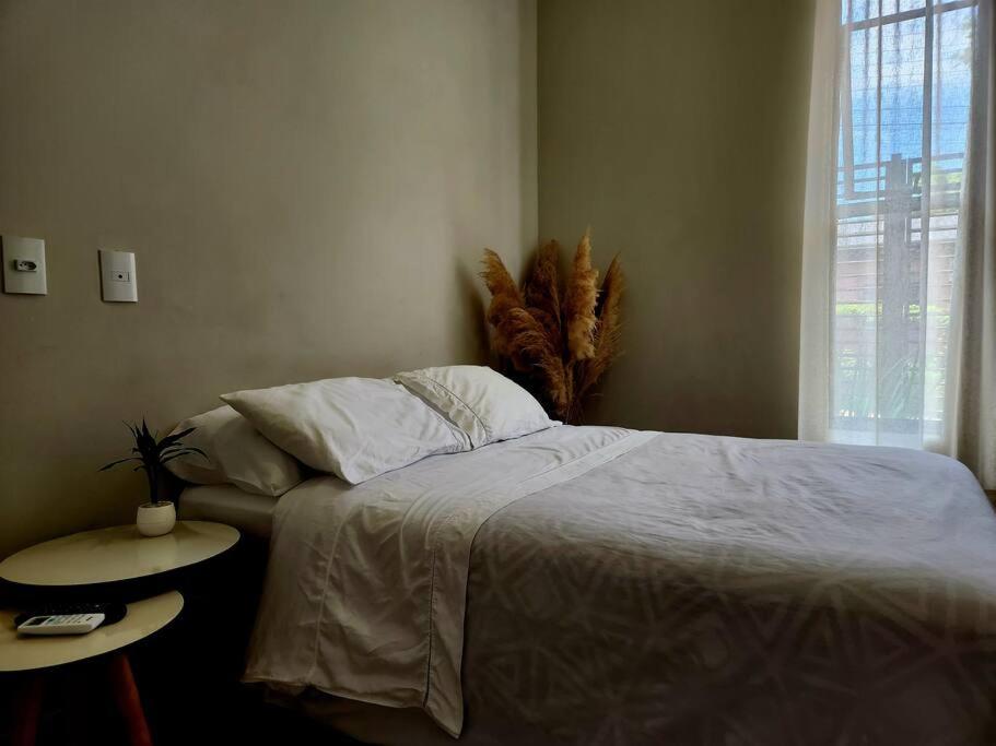 a bedroom with a bed and a table and a window at Sua casa em Foz, localização incrível in Foz do Iguaçu