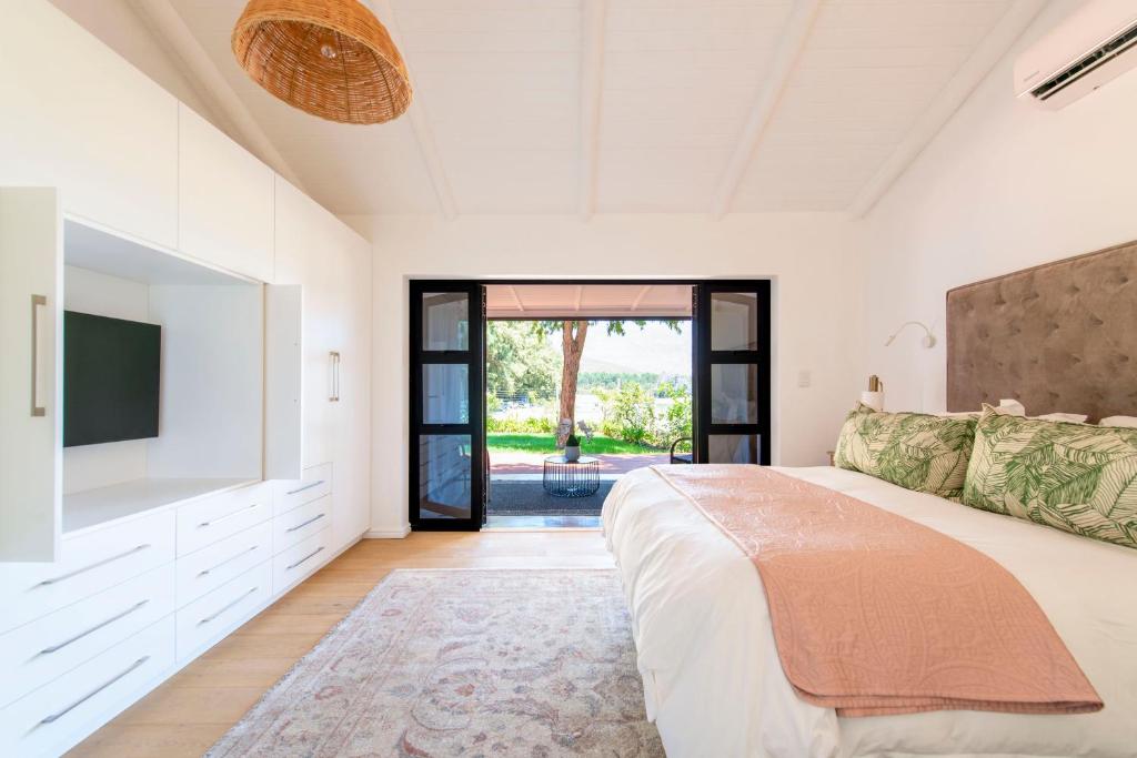 a bedroom with a large bed and a flat screen tv at Franschhoek Cottages in Franschhoek