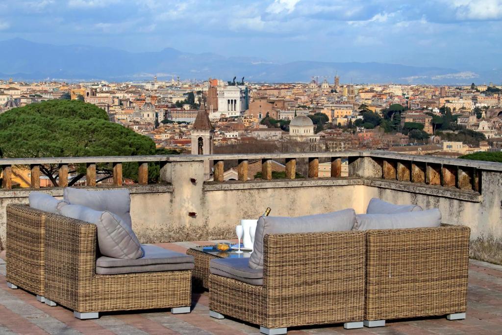 two wicker chairs and a table on a balcony overlooking a city at Domus Monamì Apartment in Rome