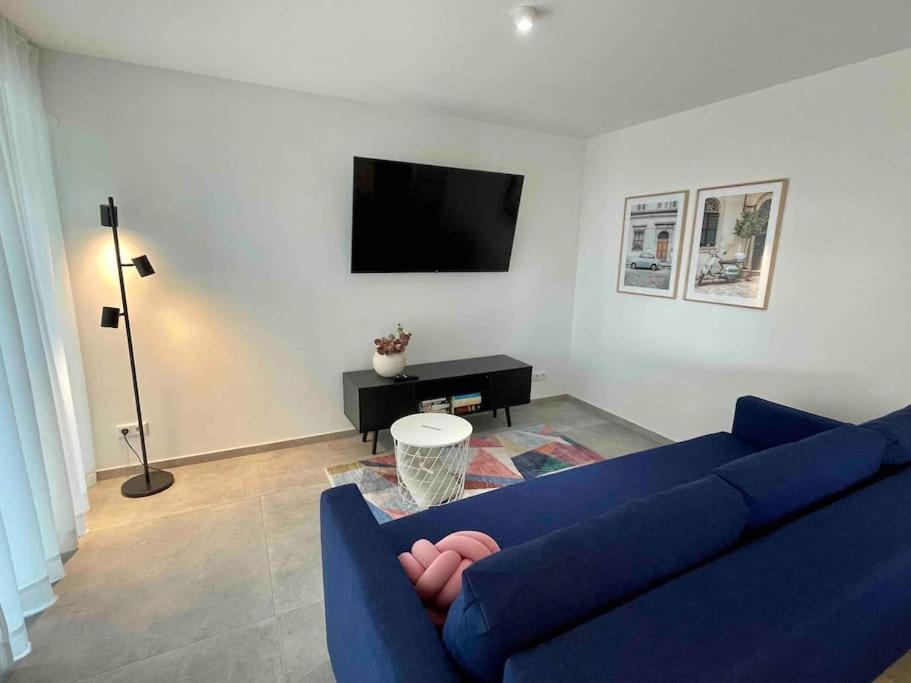 a living room with a blue couch and a tv at DaCasa-Appartement: zentral/SmartTV/24h Check in in Tamm
