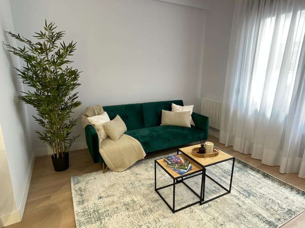 a living room with a green couch and a table at ByAndreea Apartaments EtxeBi in Guernica y Luno