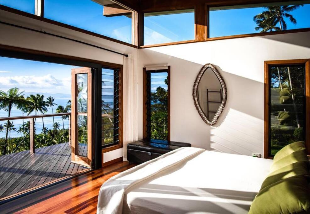 a bedroom with a large bed and large windows at Green Fiji Plantation Villa in Taveuni 