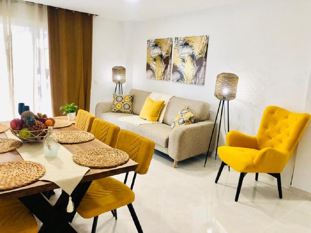 uma sala de estar com um sofá, uma mesa e cadeiras amarelas em Luxury Bahia Sea Views By Deihu Experiences em Los Cristianos