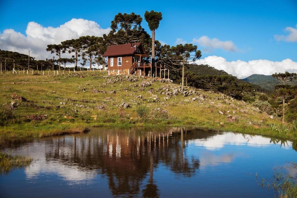 una casa sentada en la cima de una colina junto a un lago en Recanto das Águas - Urubici - SC, en Urubici