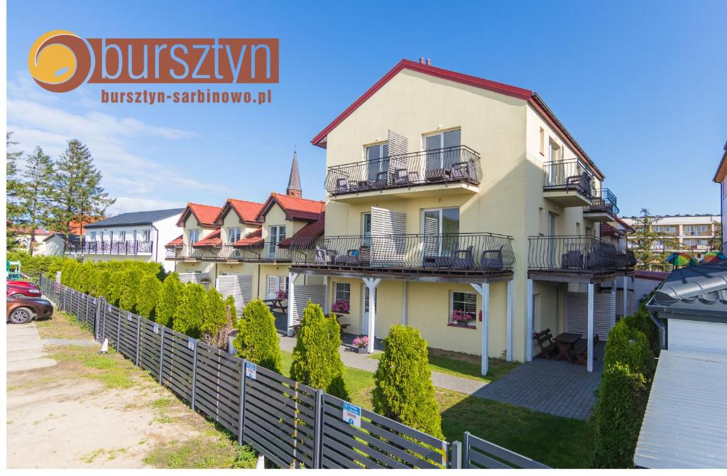 een groot huis met een hek ervoor bij Bursztyn Domki Apartamenty Pokoje w Sarbinowie blisko morza in Sarbinowo