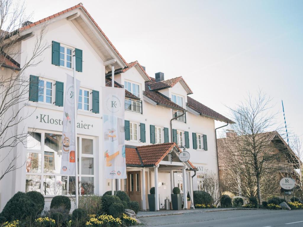 um edifício branco com persianas verdes numa rua em Klostermaier Hotel & Restaurant em Icking