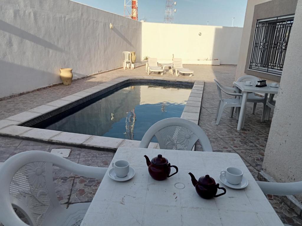 uma mesa e cadeiras ao lado de uma piscina em Villa phare 1 Midoun em Midoun