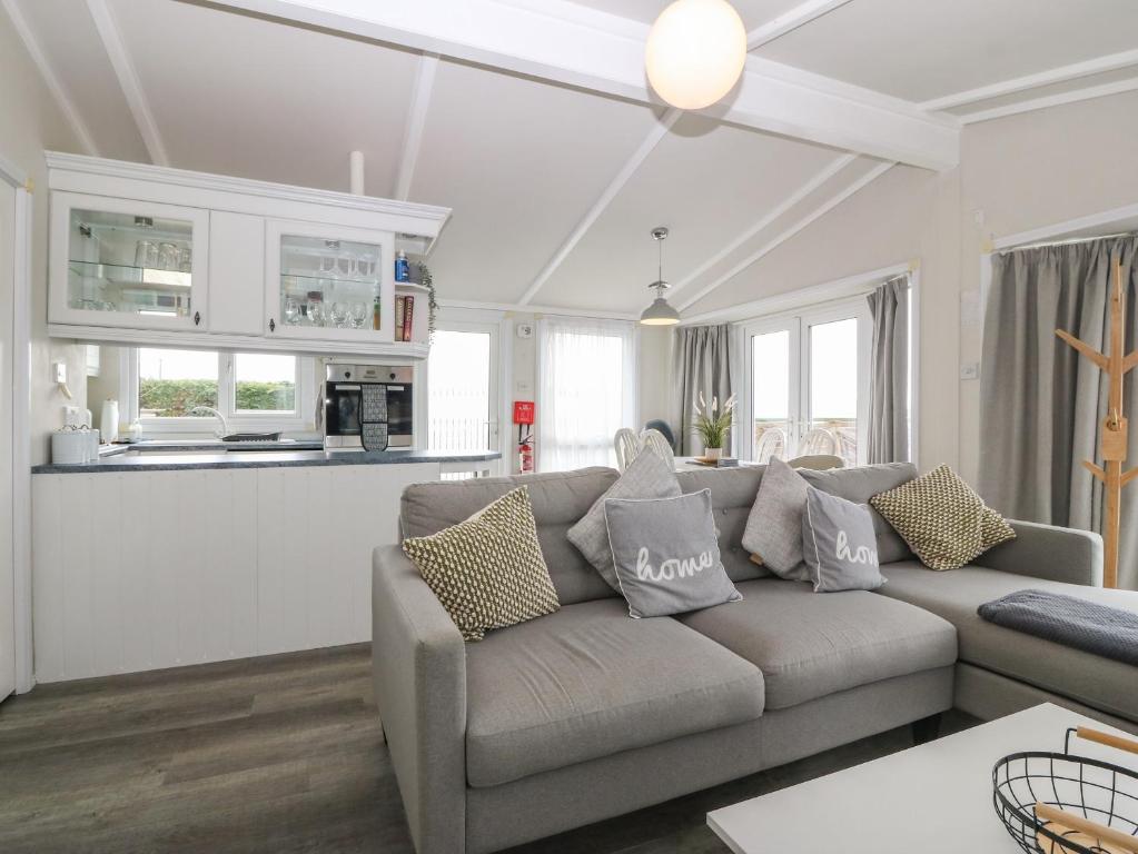 a living room with a couch and a kitchen at Caban Tywod in Pwllheli