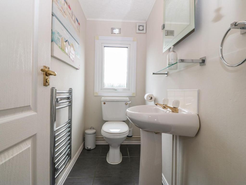 a white bathroom with a toilet and a sink at Caban Tywod in Pwllheli