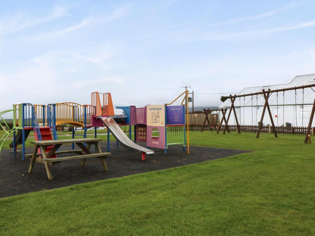 a playground with a slide in a park at Caban Tywod in Pwllheli