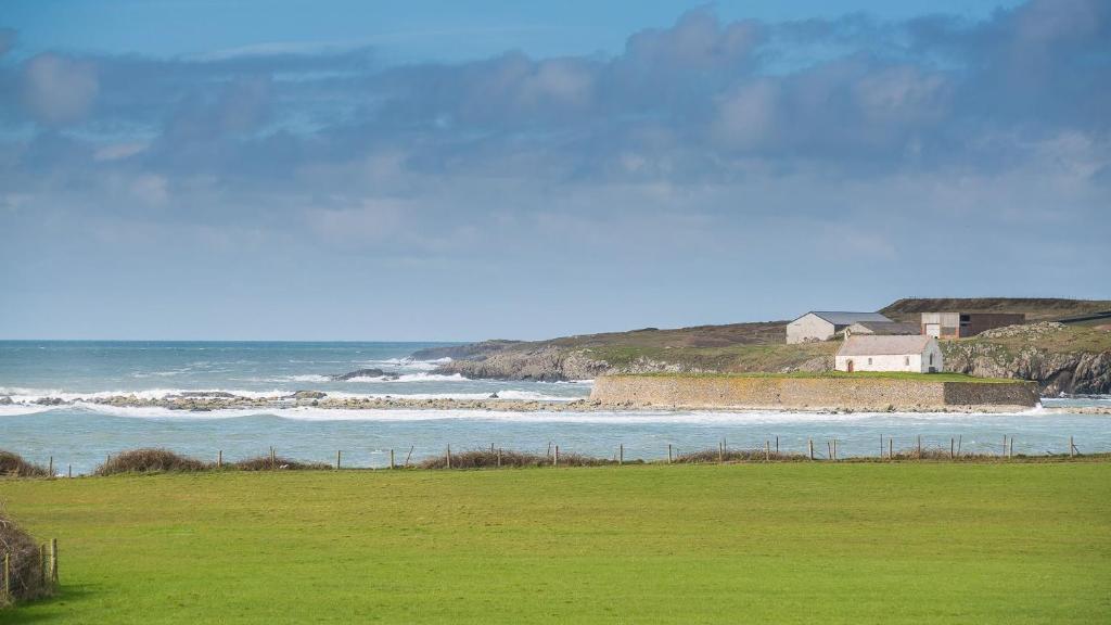 a house on a hill next to the ocean at Penrhyn Isa Un in Aberffraw