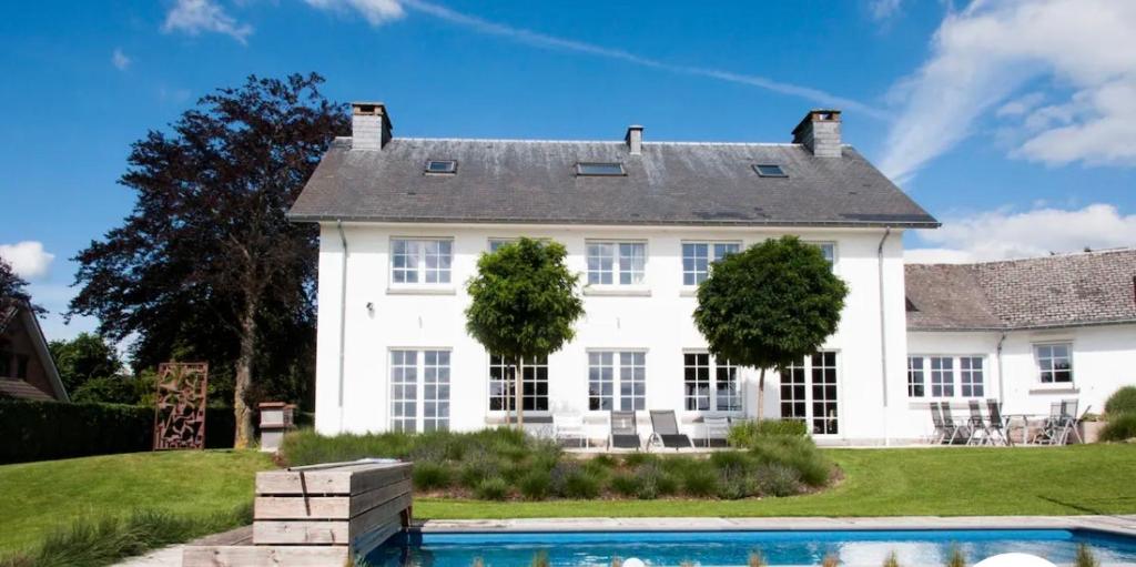 une maison blanche avec une piscine en face de celle-ci dans l'établissement Oneux Village, à Theux