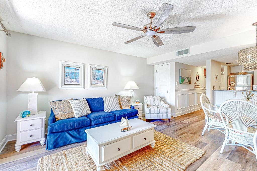 een woonkamer met een blauwe bank en een plafondventilator bij Recently updated resort condo with 2 pools, 2 balconies, ocean views, BBQ, & W/D in St. Augustine