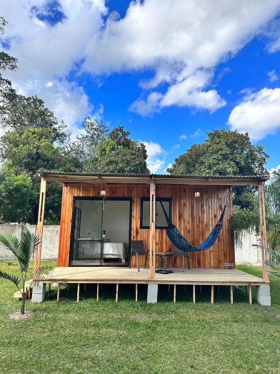 a tiny house with a hammock in a yard at Cenário Perfeito para Seu Dia Especial: Chácara Recanto do Pinheiro in Capão do Leão