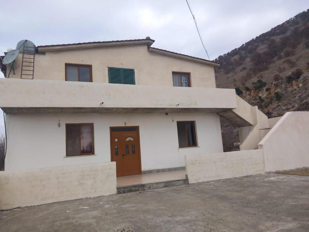 uma casa branca com uma porta castanha e uma montanha em Vila Toscana em Baks-Rrjoll