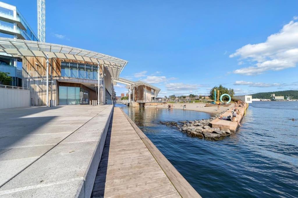 a walkway next to a building next to a body of water at Sentral modern design leilighet med 2 soverom, gratis parkering in Oslo