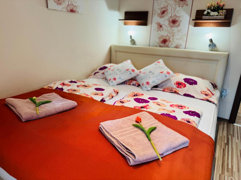 een bed met twee handdoeken en bloemen erop bij Oregano Apartmanok Siófok in Siófok