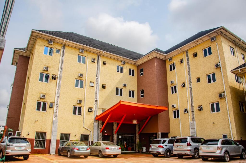 un grande edificio con macchine parcheggiate di fronte di Aify Queenest Hotel and Suites a Owerri