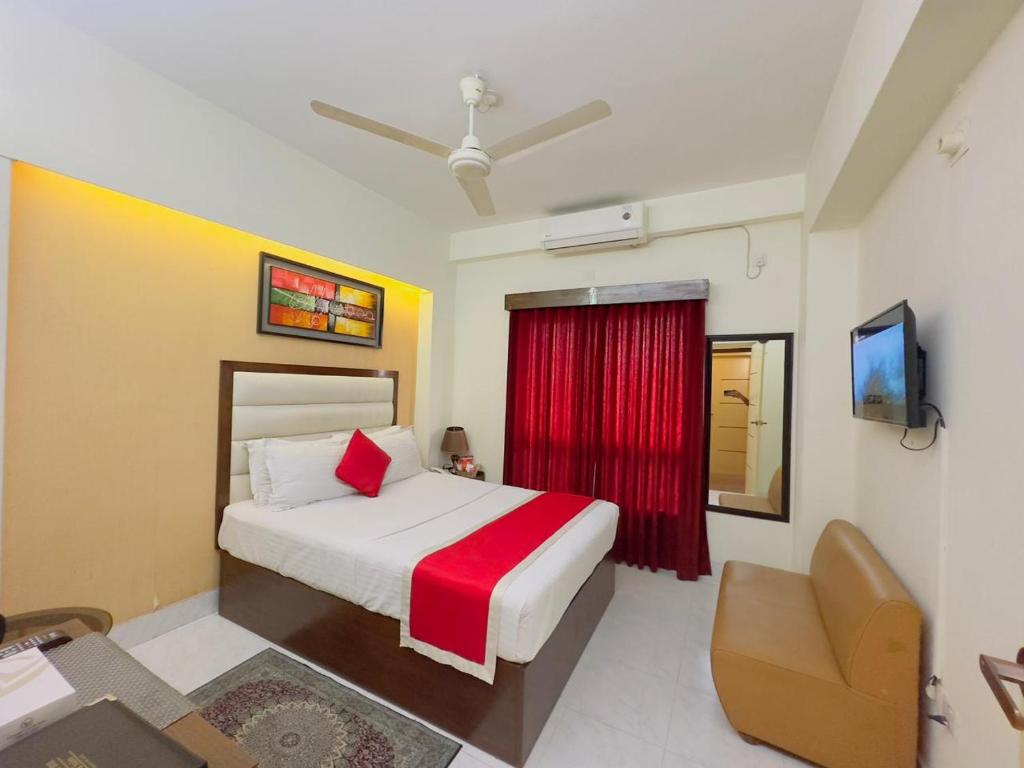 a bedroom with a bed and a chair and a television at Hotel Grand Circle Inn Dhaka in Dhaka