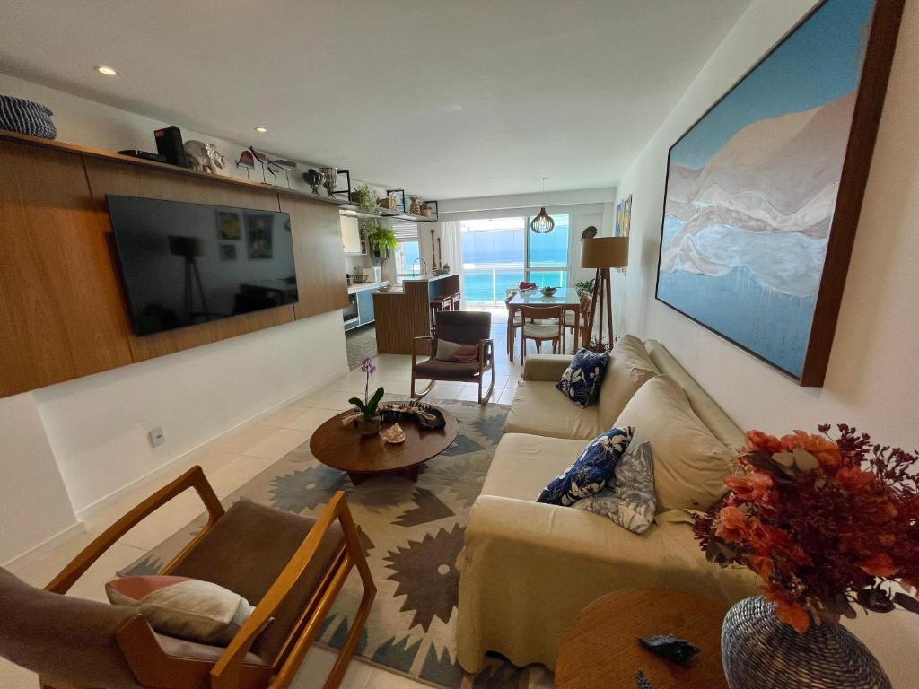 uma sala de estar com um sofá e uma sala de jantar em Frente mar- Apto pé na areia com charme e conforto no Rio de Janeiro