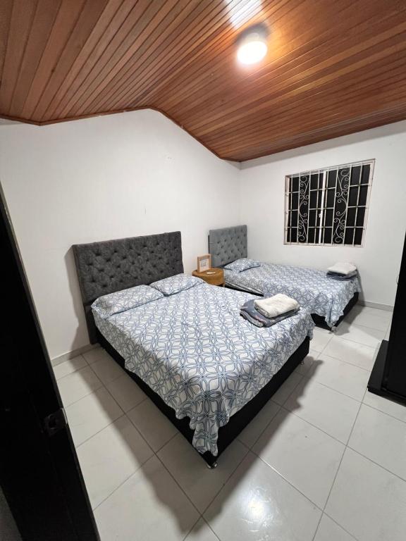 1 dormitorio con 2 camas y techo de madera en Casa frente al centro comercial Guatapuri en Valledupar