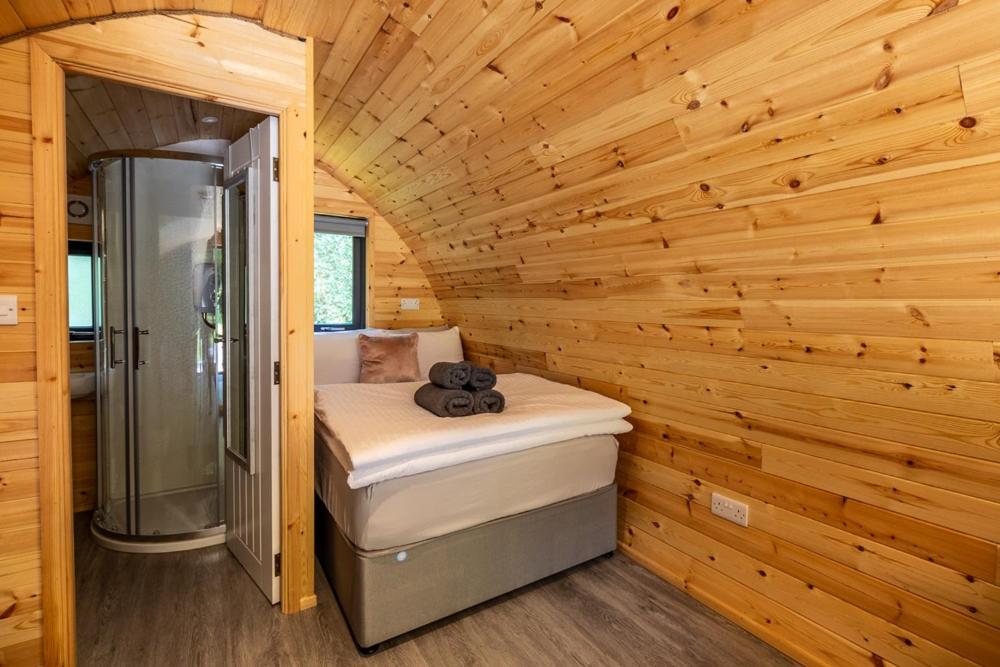 Una habitación con ducha y una cama en una cabaña de madera. en Mount Hillary Holiday Pods, en Cork