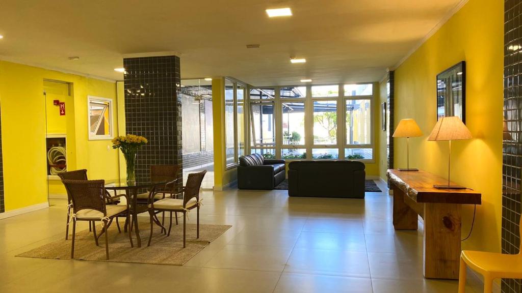 a living room with yellow walls and a table and chairs at ÓPER SMART HOTEL in Santa Maria