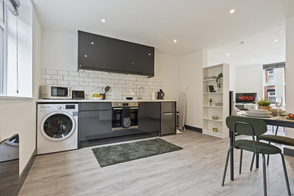 a kitchen with a washing machine and a table with chairs at The Olive Suite in Ilkeston