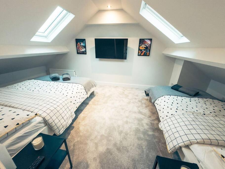a attic bedroom with two beds and a tv at Luxurious 4 Bedroom with patio in Edgware
