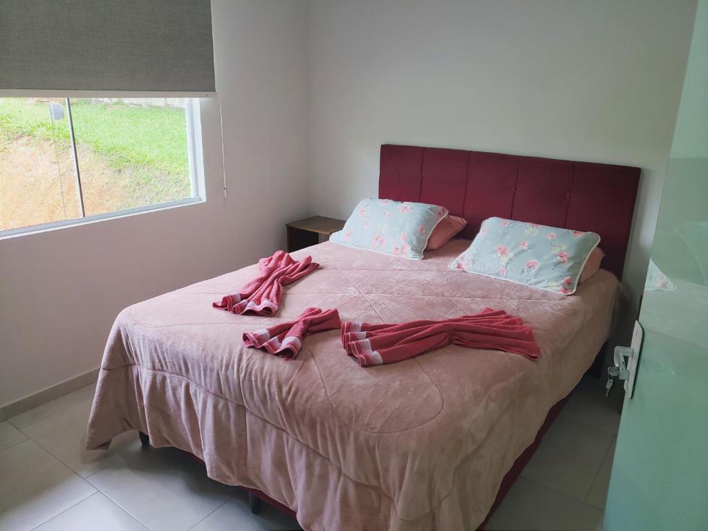 um quarto com uma cama com lençóis cor-de-rosa e uma janela em Casa Completa da Magui - 02 em Pomerode