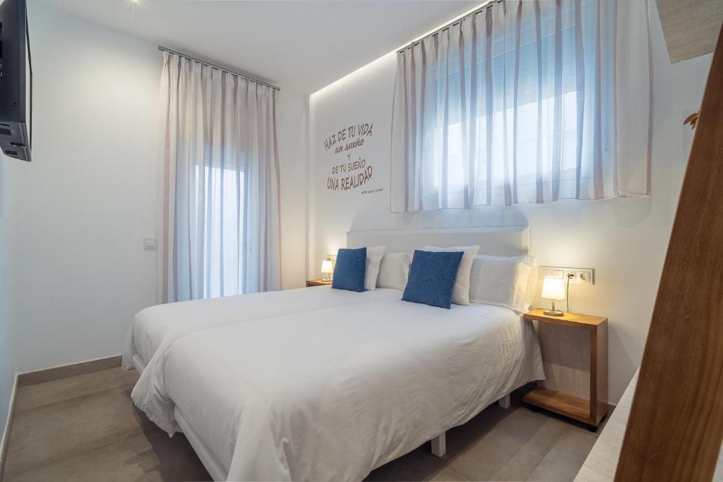 um quarto com uma grande cama branca com almofadas azuis em Apartamentos CMDreams Gold- ruinas romanas a tus pies- parking privado em Mérida