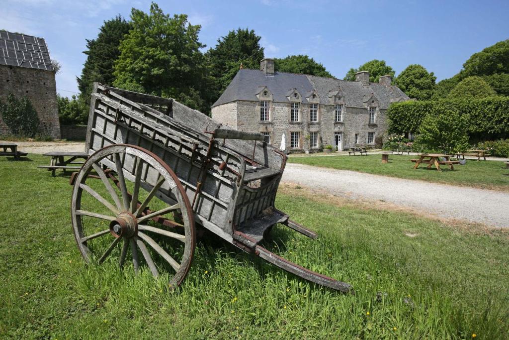 une charrette en bois assise dans l'herbe devant un bâtiment dans l'établissement Gite du Manoir des Anoteux, à Carneville