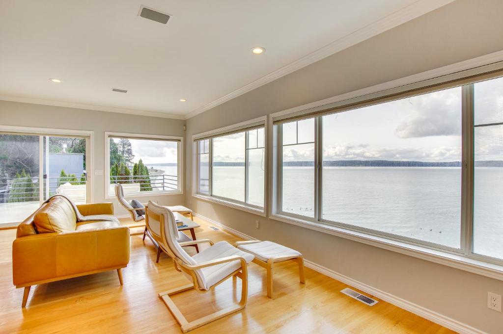 a living room with windows and a view of the water at Bright Camano Home about 4 Mi to Cama Beach State Park in Camano