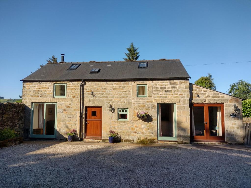 a stone house with orange doors on a driveway at Acorn Cottage, Ashover in Ashover