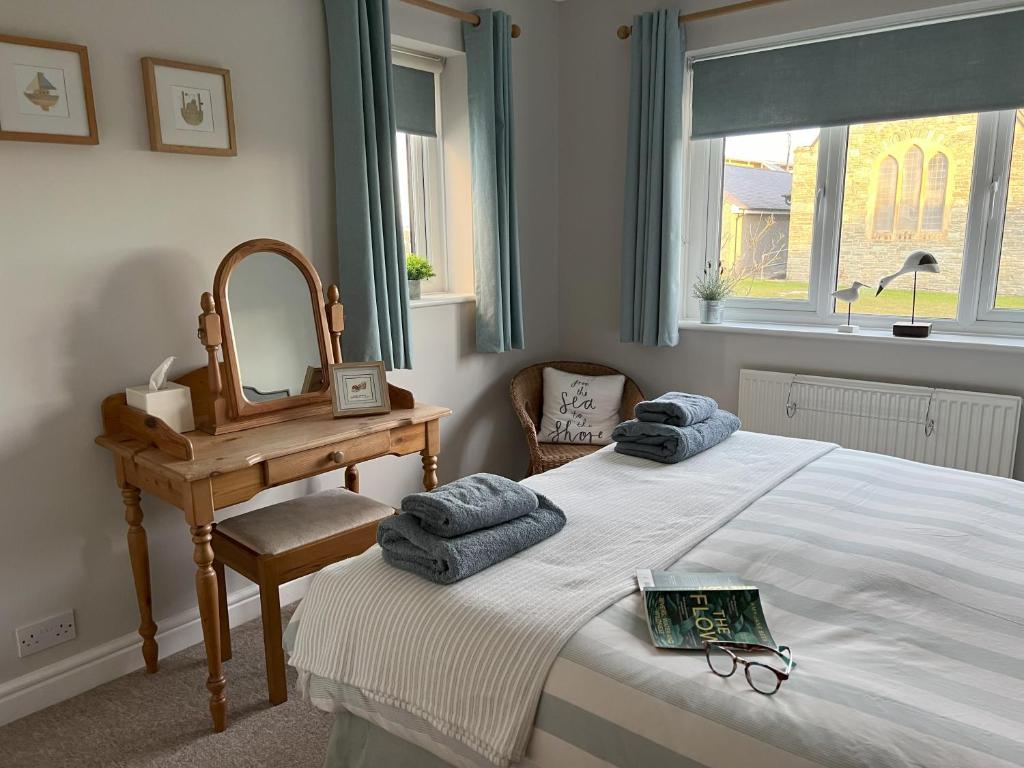 a bedroom with a bed and a desk and a mirror at Church View Anglesey in Trearddur