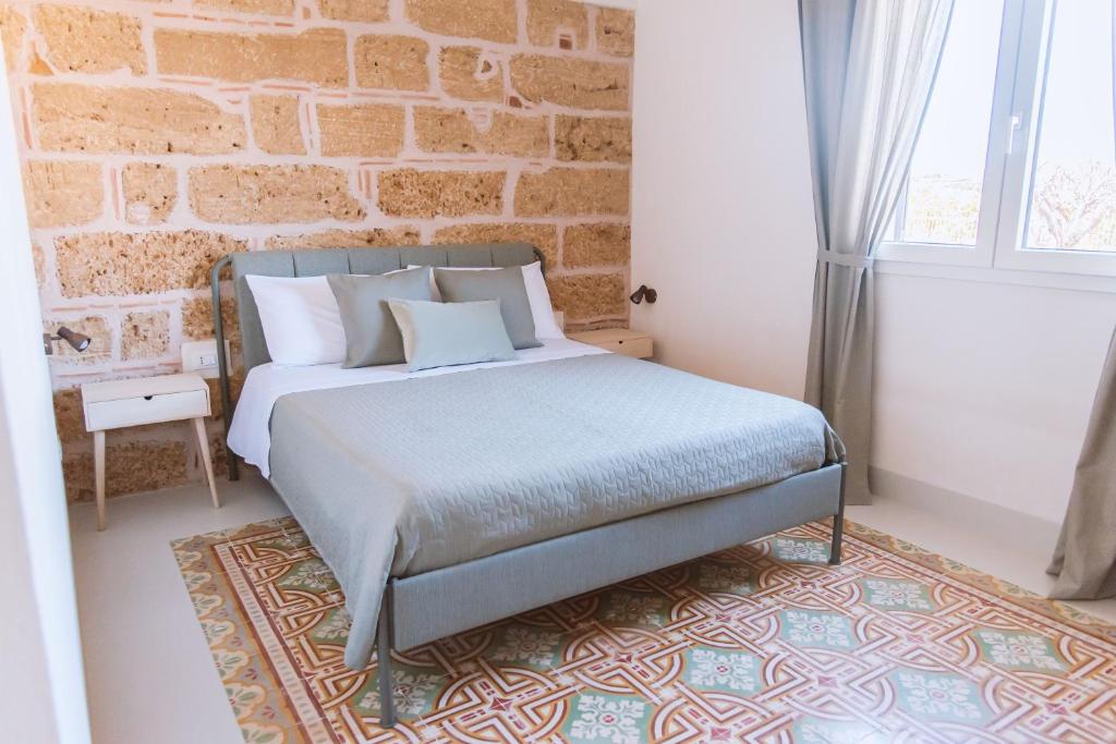 una camera con letto e muro di mattoni di Cocci di tufo Appartamenti a Rilievo