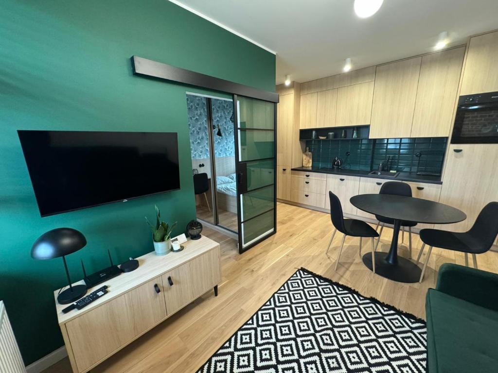 a living room with a table and a tv on a wall at Ottimo Apartamenty Długa in Bydgoszcz