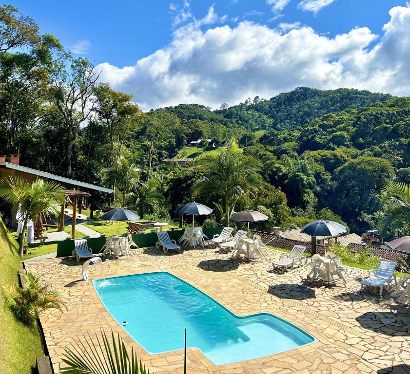 a swimming pool with chairs and umbrellas in a resort at Pousada Verdes Alpes in Santo Antônio do Pinhal