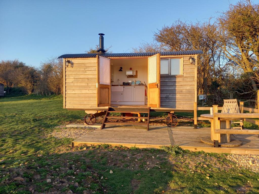 a tiny house with a picnic table and a bench at Under the Stars Shepherds Huts at Harbors Lake in Newchurch