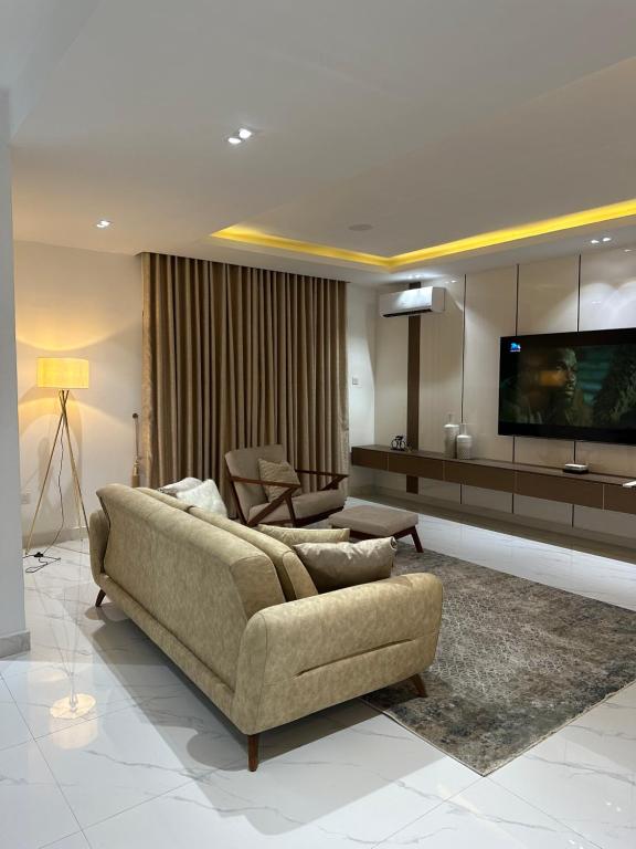 sala de estar con sofá y TV de pantalla plana en Numdor Apartments By The Bond en Port Harcourt