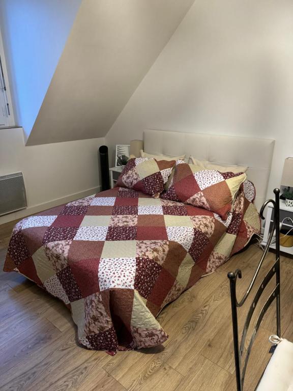 a bed with a quilt on it in a room at Studio lumineux de 35m2 au cœur de Solesmes in Solesmes