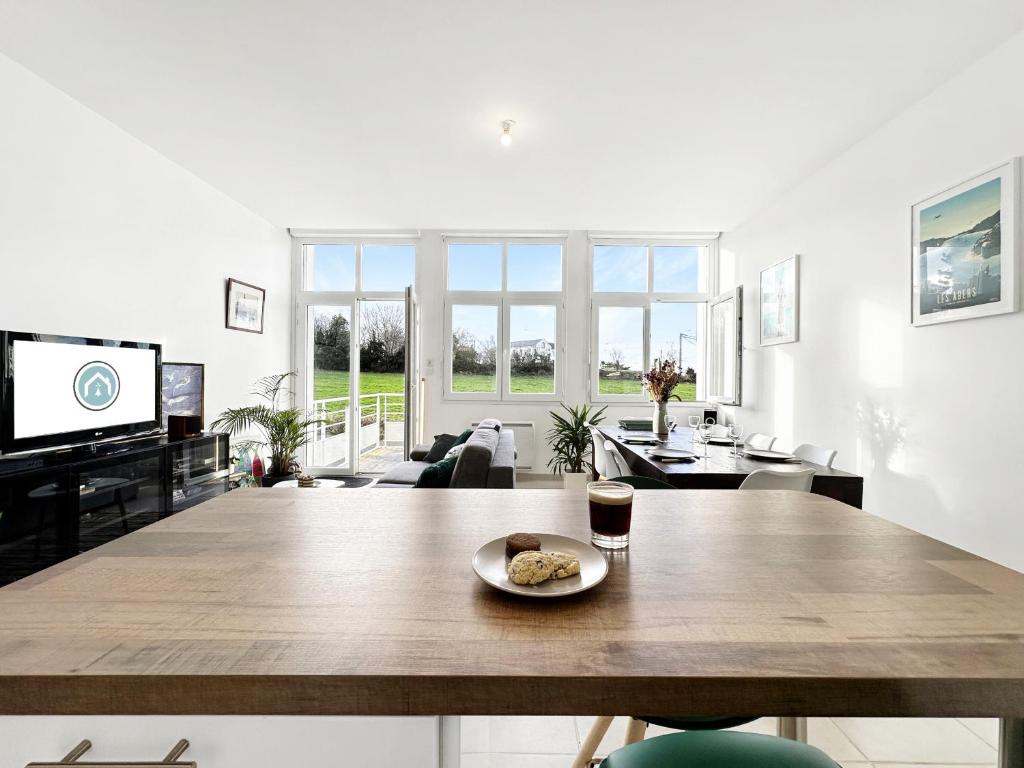un salon avec une grande table en bois et une télévision dans l'établissement Le Semaphore T2 proche mer, terrasse, balcon, à Landéda