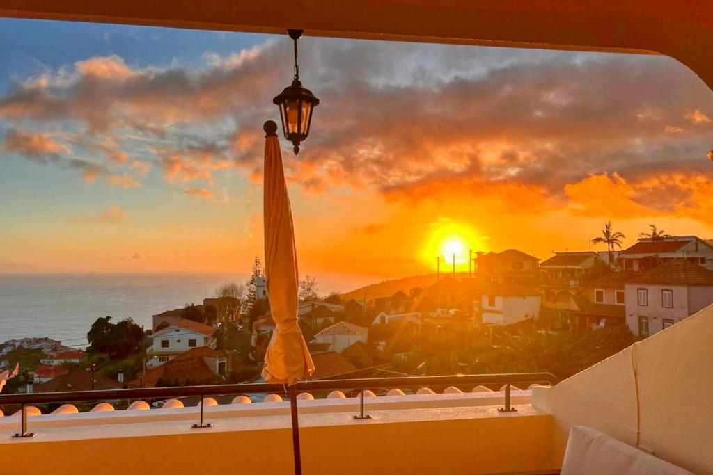 einen Blick auf den Sonnenuntergang von einem Balkon mit Sonnenschirm in der Unterkunft Por do Sol, a Home in Madeira in Ponta do Sol