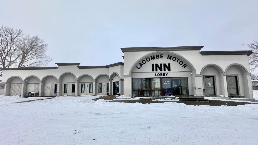 a building with a store in the snow at Lacombe Motor Inn in Lacombe
