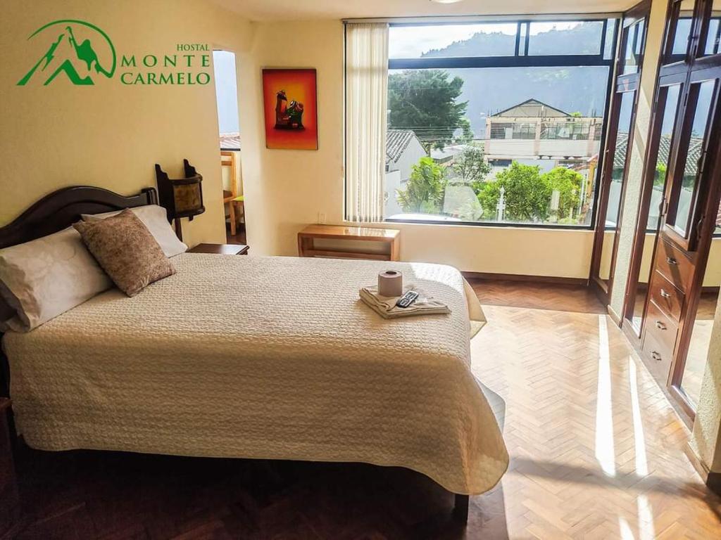 ein Schlafzimmer mit einem großen Bett und einem großen Fenster in der Unterkunft Hostal Monte Carmelo in Baños