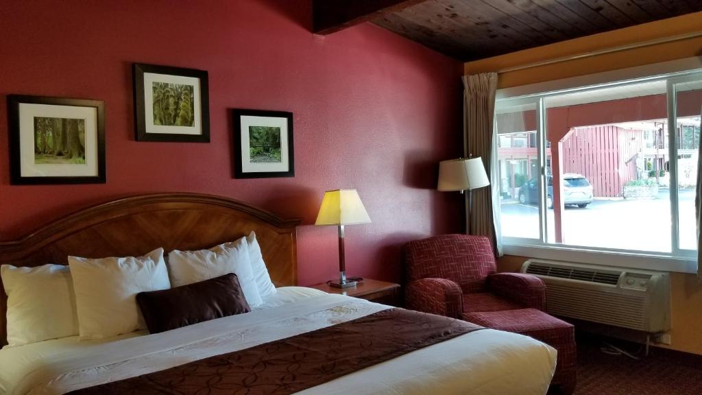 a bedroom with a bed and a chair and a window at Forks Motel in Forks