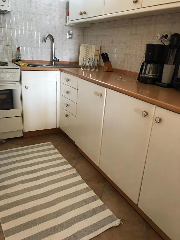 kuchnia z białymi szafkami i dywanem kuchennym w obiekcie Mola Kalyva SeaView Mesidrili w mieście Mola Kalyva