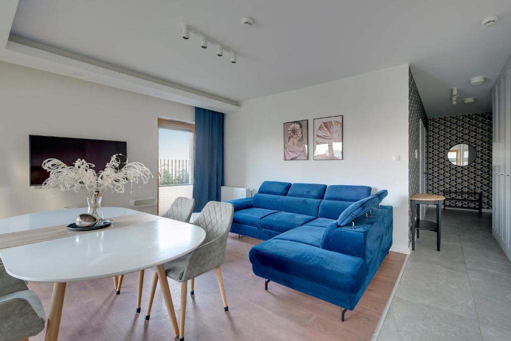 a living room with a blue couch and a table at Welcome Gdańsk Apartaments Nadmotławie Gym and Sauna in Gdańsk