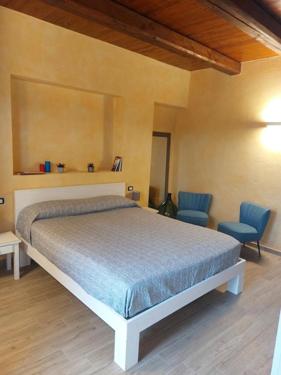 ein Schlafzimmer mit einem Bett und zwei blauen Stühlen in der Unterkunft AGRITURISMO DA RICCARDO in Bossolasco